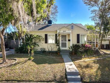 Charming yellow bungalow with a landscaped front yard and mature trees, offering curb appeal and a welcoming entrance at 2107 University Dr, Orlando, FL 32804