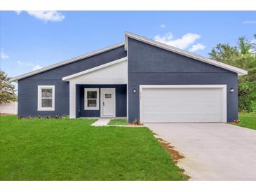 Modern home featuring a blue exterior, white trim, and a well-manicured lawn at 4761 Sw 142Nd Place Rd, Ocala, FL 34473
