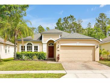 Charming home with a lush green lawn, mature landscaping, and a brick driveway at 9457 Candice Ct, Orlando, FL 32832