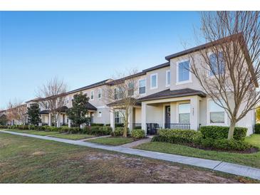 View of row of townhomes with well-manicured lawns and mature trees in a residential community at 9743 Amber Chestnut Way, Winter Garden, FL 34787