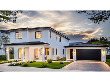 Beautiful two-story white home with a manicured lawn, a black roof, and a two-car garage at 231 Page St, Orlando, FL 32806