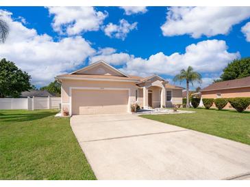 Inviting single-story home with a two-car garage, well-maintained lawn, and a lengthy driveway under a partly cloudy sky at 2712 Pearl Court, Kissimmee, FL 34743