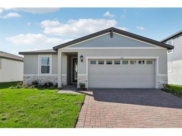 Charming single-Gathering home with a two-car garage, brick driveway, manicured lawn, and stone accents at 317 Castle Dr, Lake Alfred, FL 33850