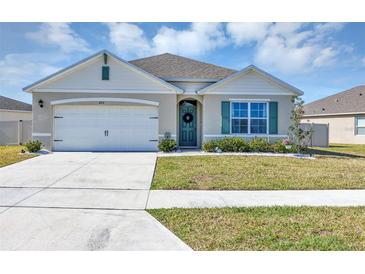 Charming single-story home featuring a two-car garage, well-maintained lawn, and a welcoming front door with wreath at 493 Talisi Loop, St Cloud, FL 34771