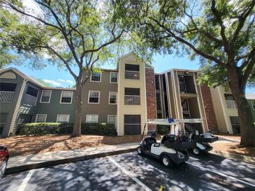 View of the building's exterior with multiple floors, balconies, golf carts, and ample parking space at 5064 Park Central Dr # 1731, Orlando, FL 32839