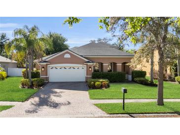 Charming single-story home with a well-manicured lawn, paver driveway, and attached two-car garage at 5108 Legacy Oaks Dr, Orlando, FL 32839
