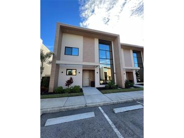 Modern townhome featuring clean architectural lines, a private entrance, and lush landscaping at 7465 Bleecker Ln, Kissimmee, FL 34747