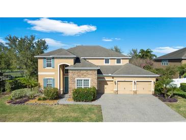Charming two-story home boasts a three-car garage, stone accents, manicured landscaping, and traditional architectural design at 2015 Sandy Garden Ln, Winter Garden, FL 34787