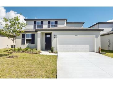 Two-story home featuring a well-manicured lawn, dark shutters, and a two-car garage at 2098 Rosewood Dr, Bartow, FL 33830