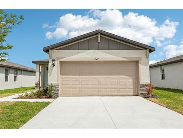 Exterior of home featuring a two-car garage and stone accents on the facade under a blue sky at 2507 Linda Knoll Ln, Bartow, FL 33830