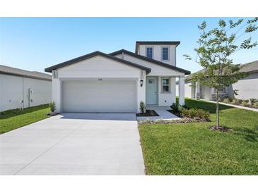 Charming home with a two-car garage, manicured lawn, and a light blue front door at 2518 Linda Knoll Ln, Bartow, FL 33830