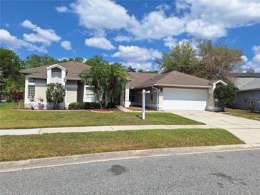Charming single-story home with a well-manicured lawn, mature trees, and attached two-car garage on a sunny day at 3125 Timucua Cir, Orlando, FL 32837