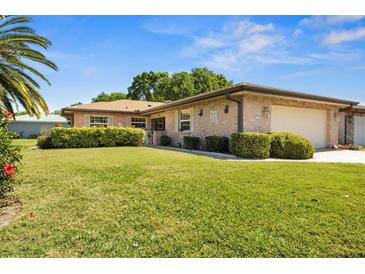 Inviting brick home with attached garage, lush lawn and landscaping under clear skies at 398 Troon Ct, Winter Haven, FL 33884