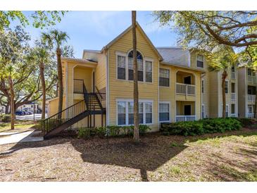 Inviting yellow condo with black staircase, mature trees, and well-maintained landscaping for a serene outdoor experience at 1017 S Hiawassee Rd # 3718, Orlando, FL 32835