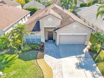 Beautiful single-story home with lush landscaping, brick pathway, and a two-car garage at 14228 Portrush Dr, Orlando, FL 32828