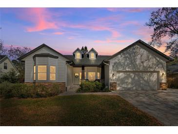 Charming home featuring white siding, stone accents, and a well-manicured lawn against a twilight sky at 1667 Spring Loop Way, Winter Garden, FL 34787