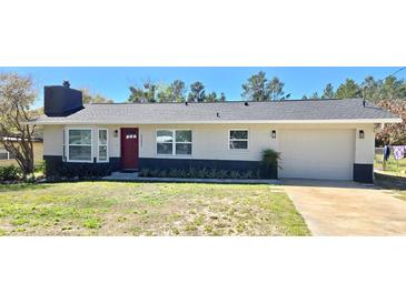 Charming single-story home with a red front door, a chimney, and an attached one car garage at 32803 Forest Ave, Leesburg, FL 34788