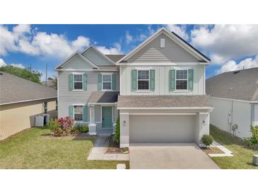 Charming two-story home featuring a two-car garage, well-maintained lawn, and tasteful green shutter accents at 520 Pinecrest Loop, Davenport, FL 33837