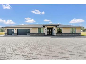 Attractive single-story home showcasing stone accents, a three-car garage, and a spacious paved driveway at 12323 Sweet Hill Rd, Polk City, FL 33868