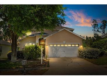 Charming single-Gathering home with a well-manicured lawn and an attached two-car garage at dusk at 229 Troon Cir, Davenport, FL 33897