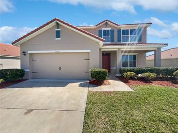 Two-story home with red tile roof, tan exterior, blue shutters, landscaping, and a two car garage at 3056 Sangria St, Kissimmee, FL 34744