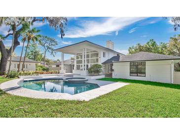 This backyard features a sparkling pool and spa, surrounded by lush greenery and a patio area at 409 W 2Nd Ave, Windermere, FL 34786