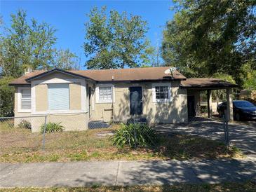 Charming single-story home with a tan exterior, chain-link fence, and covered parking at 4553 Piedmont St, Orlando, FL 32811