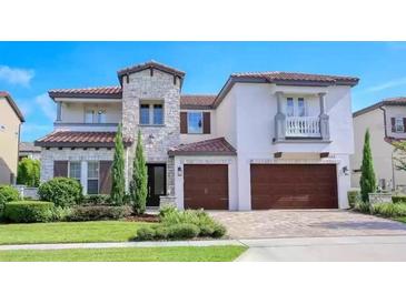 Beautiful two-story home with a stone facade, two-car garage, well-manicured lawn, and a stylish balcony at 688 Canopy Estates Dr, Winter Garden, FL 34787