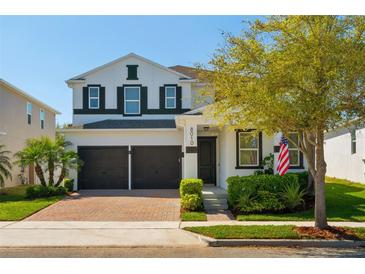 Charming two-story home with a brick driveway, two-car garage, and well-manicured landscaping under a clear blue sky at 8010 Soldierwood St, Winter Garden, FL 34787