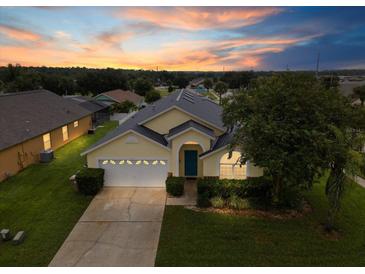 Inviting one-story home featuring a two-car garage, blue front door, and lush landscaping at 8073 Santee Dr, Kissimmee, FL 34747
