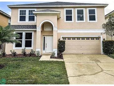 Two-story home showcasing the front yard with lush green lawn, complemented by landscaping and a two-car garage at 10071 Cypress Knee Cir, Orlando, FL 32825