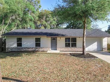 Charming single-story home featuring a well-maintained lawn, gray door, and attached two-car garage at 145 W Fern Dr, Orange City, FL 32763