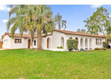 Charming Spanish-style home featuring a white exterior, arched entryways, and a lush green lawn at 3052 Saratoga Dr, Orlando, FL 32806