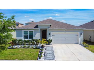 Inviting single-story home features a manicured lawn, tasteful landscaping, and a two-car garage at 460 Lily Ln, Davenport, FL 33837