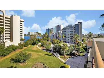 Scenic aerial view of lush landscaping, community pool, and high-rise condominiums under a partly cloudy blue sky at 6165 Carrier Dr # 3512, Orlando, FL 32819