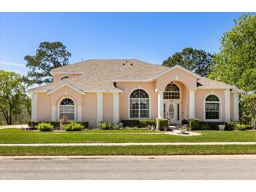 Charming single-story home featuring a manicured lawn, arched windows, and a light peach exterior at 6651 Sylvan Woods Dr, Sanford, FL 32771