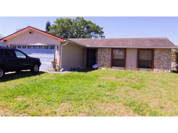 Cozy single-story home featuring stone accents, blue garage door, and spacious front lawn at 7717 Pineapple Dr, Orlando, FL 32835