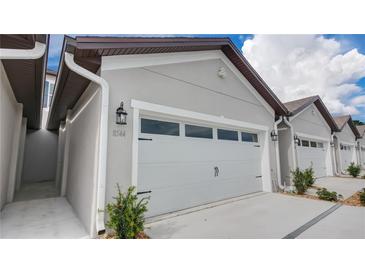 Attached two-car garage featuring carriage door design and exterior lighting fixtures at 8544 Magnificent Ln, Groveland, FL 34736