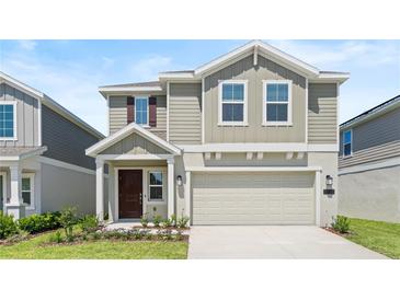 Charming two-story home with a well-maintained lawn and a two-car garage, painted in neutral tones at 128 Adventure Ave, Davenport, FL 33837