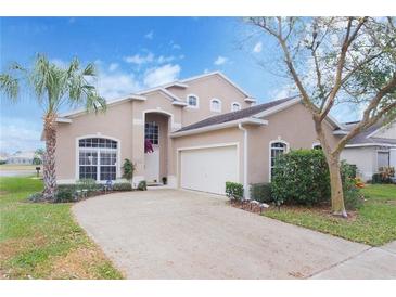 Charming two-story home with a well-maintained lawn, mature trees, and a circular driveway leading to the garage at 252 Julliard Blvd, Davenport, FL 33897