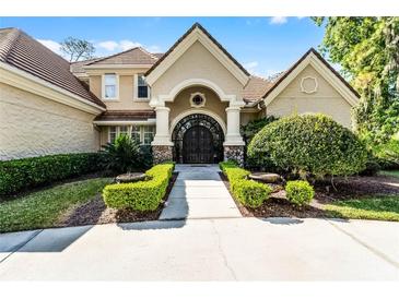 Stately home exterior featuring a grand arched entrance, manicured landscaping, and a tile roof at 257 New Gate Loop, Lake Mary, FL 32746