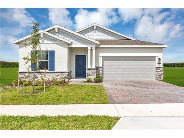 Charming single-story home with brick driveway, blue door, and manicured lawn under a partly cloudy sky at 4113 Jespersen St, Apopka, FL 32712