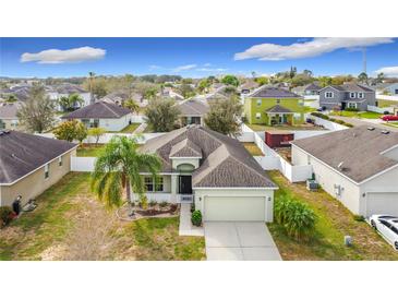 An aerial view of a charming single-story home with a well-maintained lawn and a two-car garage at 673 Highland Meadows Ave, Davenport, FL 33837