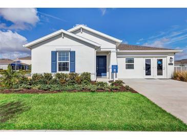 Inviting single-story home featuring a manicured lawn, blue shutters, and a charming front entrance at 945 Laurel View Way, Groveland, FL 34736