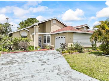 Inviting single-story home featuring a charming front yard, driveway, and attached garage at 165 Coralwood Cir, Kissimmee, FL 34743