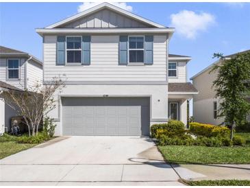 Charming two-story home with a gray stucco exterior, blue shutters, and well-manicured landscaping at 17394 Million Lakes Ct, Clermont, FL 34714