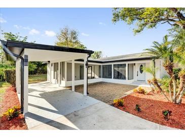 Charming single-story home featuring a carport, brick-paved patio, and tropical landscaping at 2012 Dorris Dr, Orlando, FL 32807