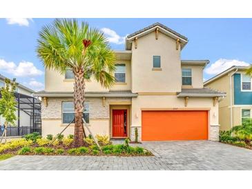 Inviting two-story home featuring a vibrant orange garage door and a lush palm tree in the front yard at 2557 Shanti Dr, Kissimmee, FL 34746