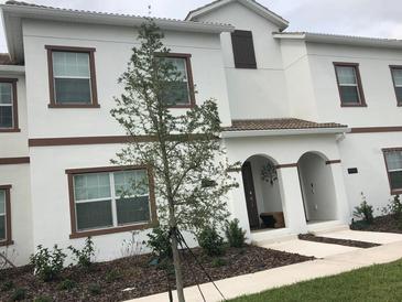 Charming two-story home with a white exterior, brown trim, arched entryway and well-maintained landscaping at 4949 Windermere Ave, Kissimmee, FL 34746