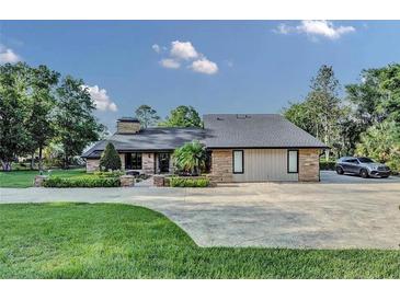 Beautiful single-story home with stone accents, lush landscaping, and a spacious driveway at 6115 Linneal Beach Dr, Apopka, FL 32703